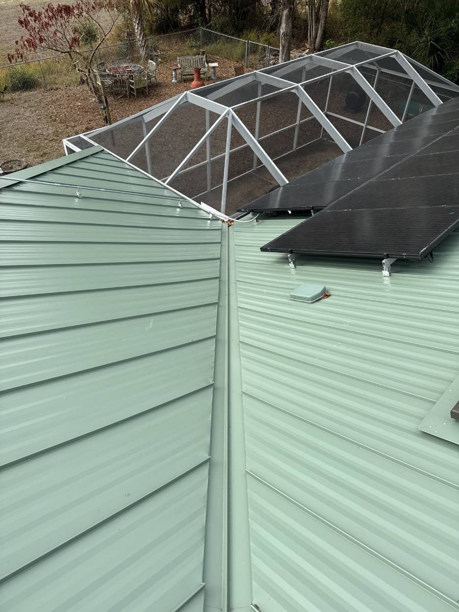 Sage green metal roof with solar panels and pool enclosure by Hippo Roofing, Brevard County, FL