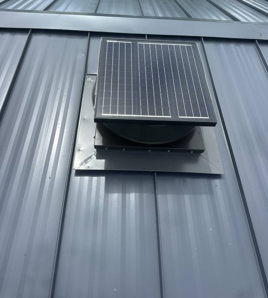 Dark gray standing seam metal roof with solar attic fan installed by Hippo Roofing in Rockledge, FL