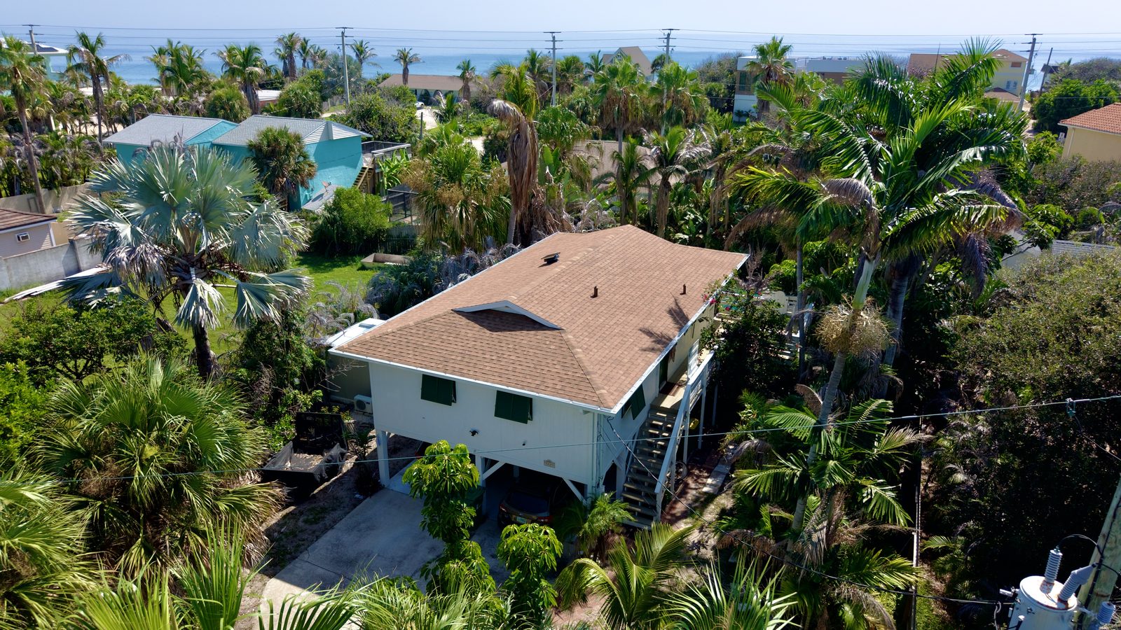 Aerial view of a completed shingle roof replacement on an elevated beachfront home in Melbourne Beach, Florida
